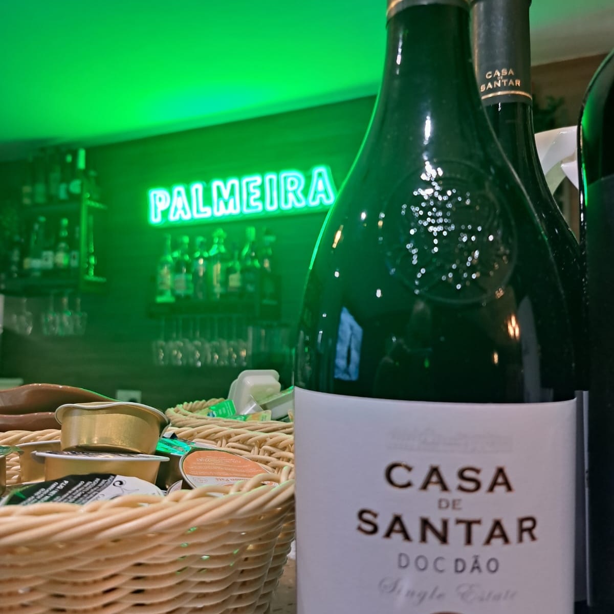 The Palmeira bar under its green neon sign, with a bottle of Portuguese Casa de Santar wine on the counter